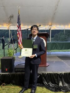 Ethan Yan with his Coolidge Senator certificate in a field in the Vermont hills