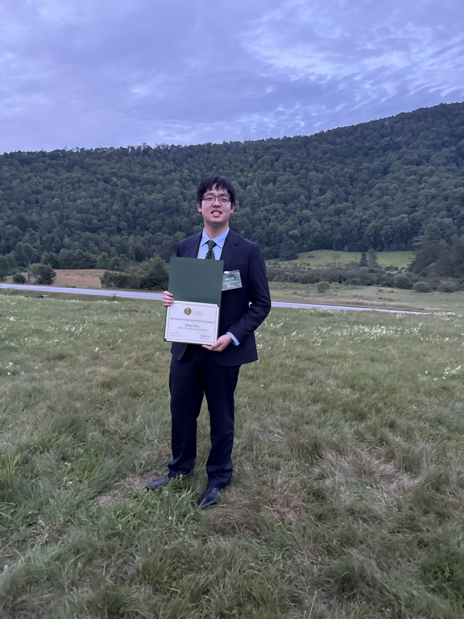 Ethan Yan holding his 2026 Coolidge Senator certificate under the ceremony tent